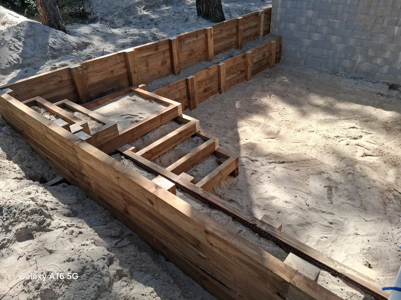 Construction d'une terrasse en bois avec escalier intégré sur sol sableux