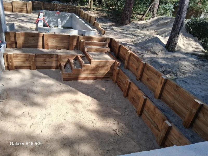 Vue d'ensemble du chantier : terrasse bois, escalier et bassin en construction